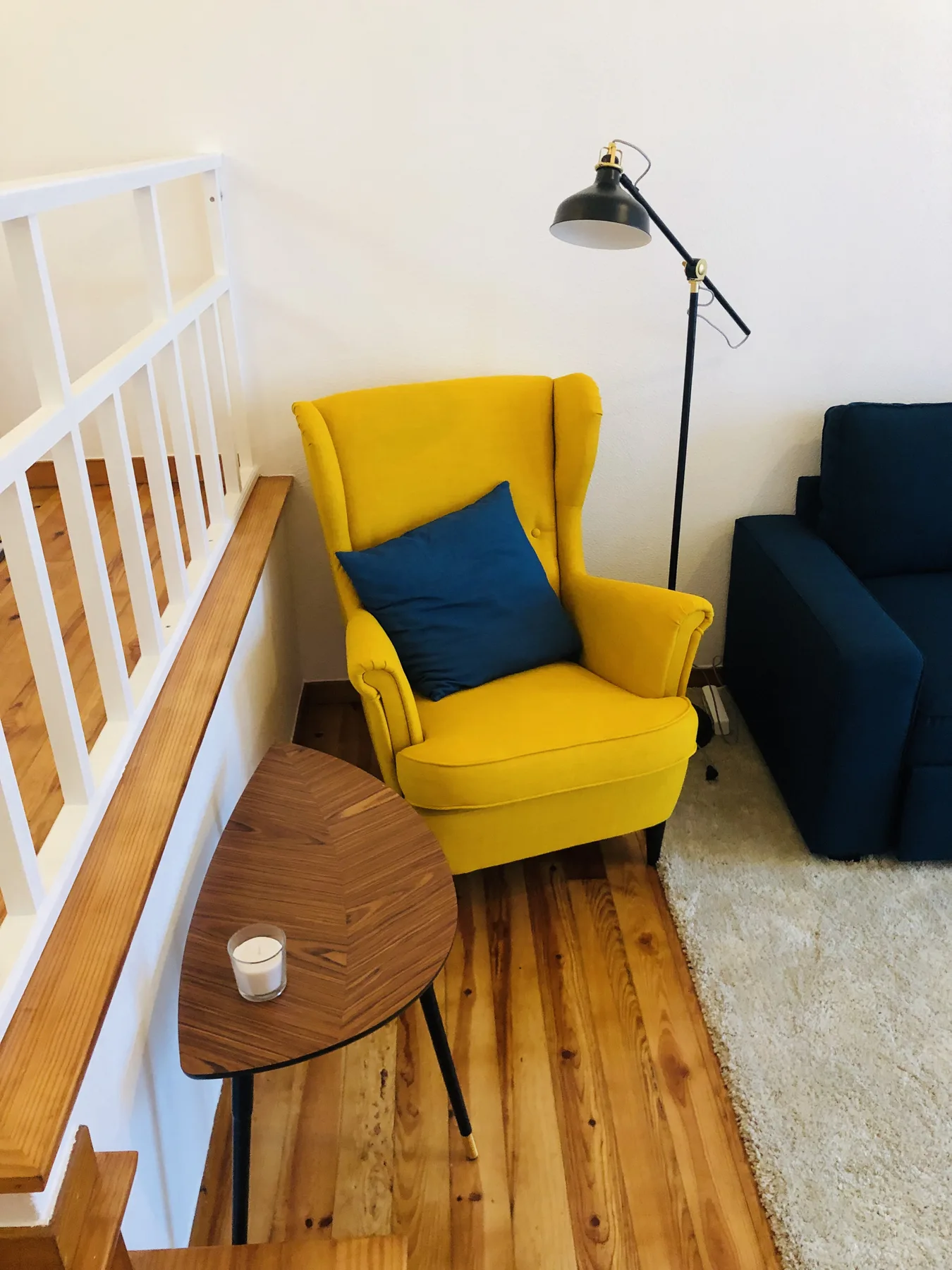 A living room with a yellow armchair, a small table, and a floor lamp.