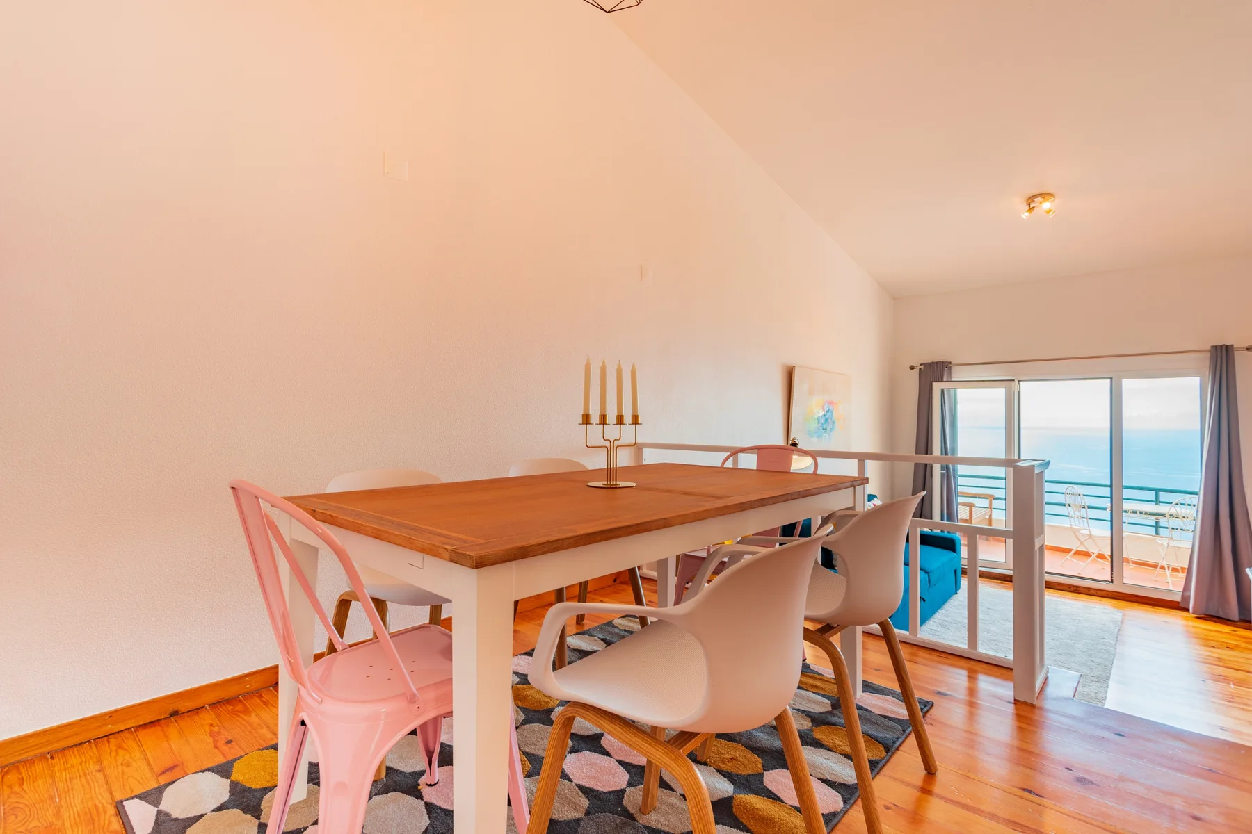 Dining area with a table and chairs beside large windows overlooking the ocean.
