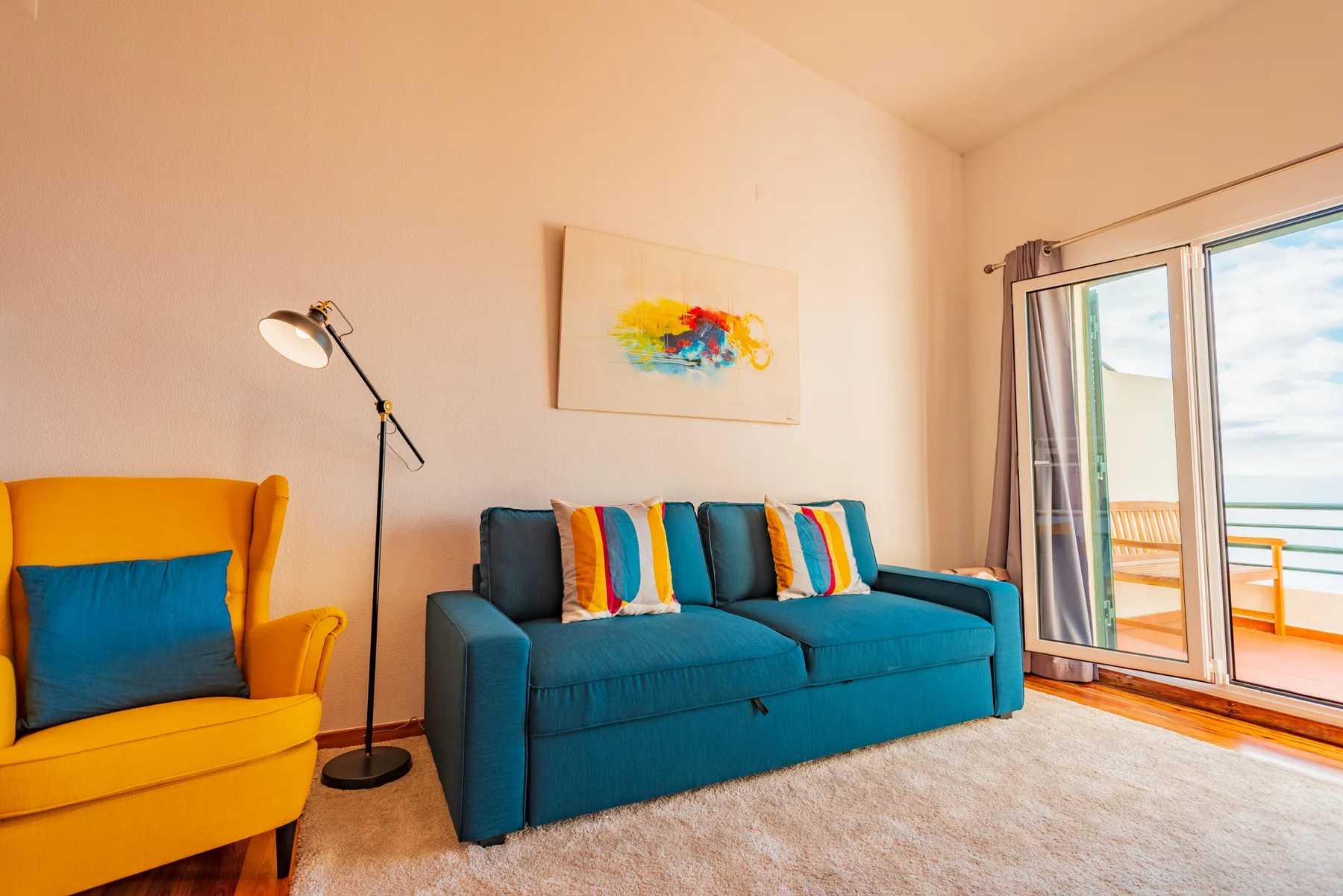 A living room with colorful seating beside open sliding glass doors.