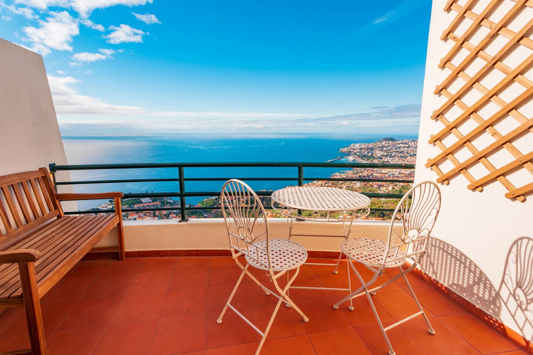 A terrace with a table and seating overlooks the ocean and coastline.