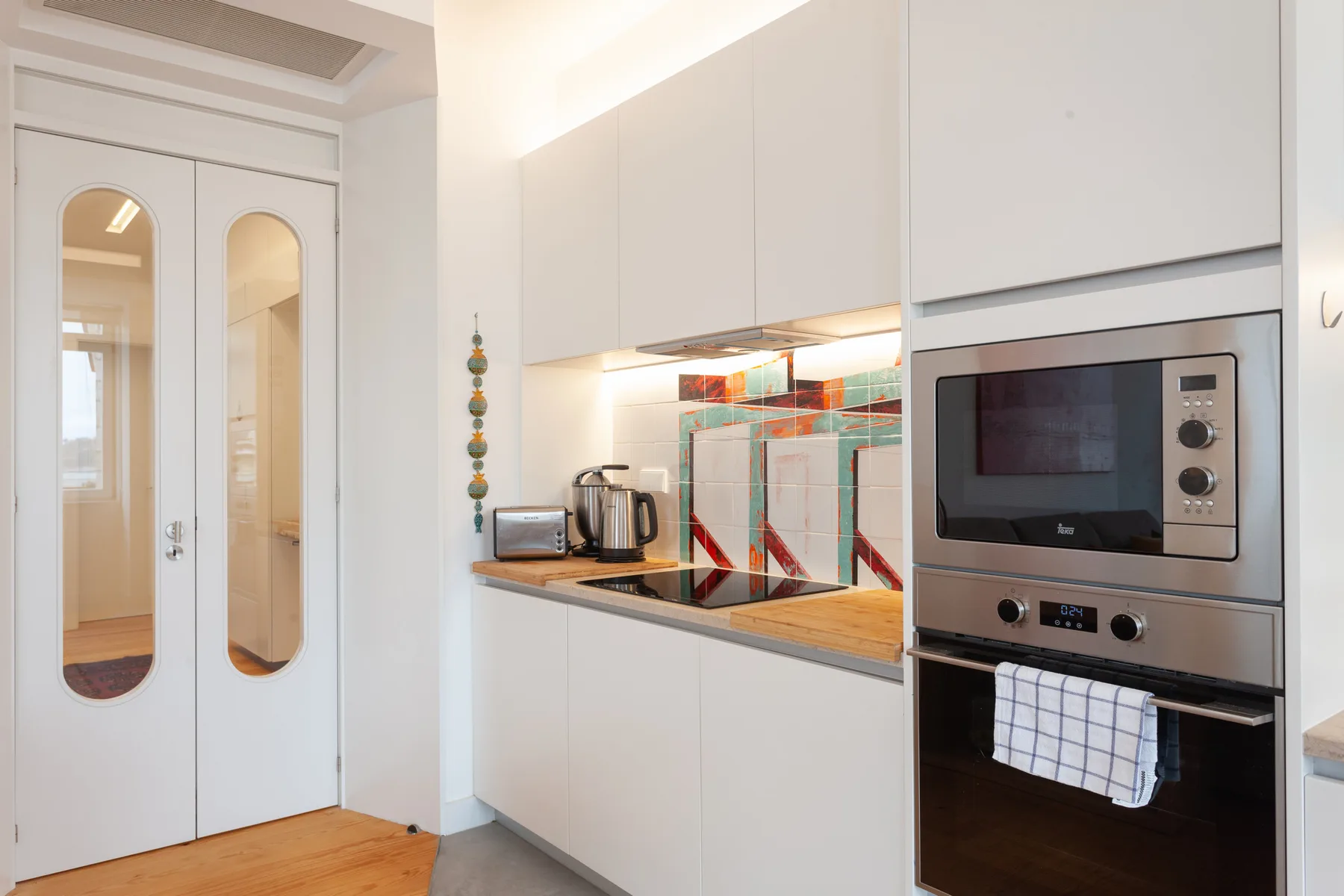 Una cocina moderna y luminosa con armarios blancos, una encimera y electrodomésticos integrados.