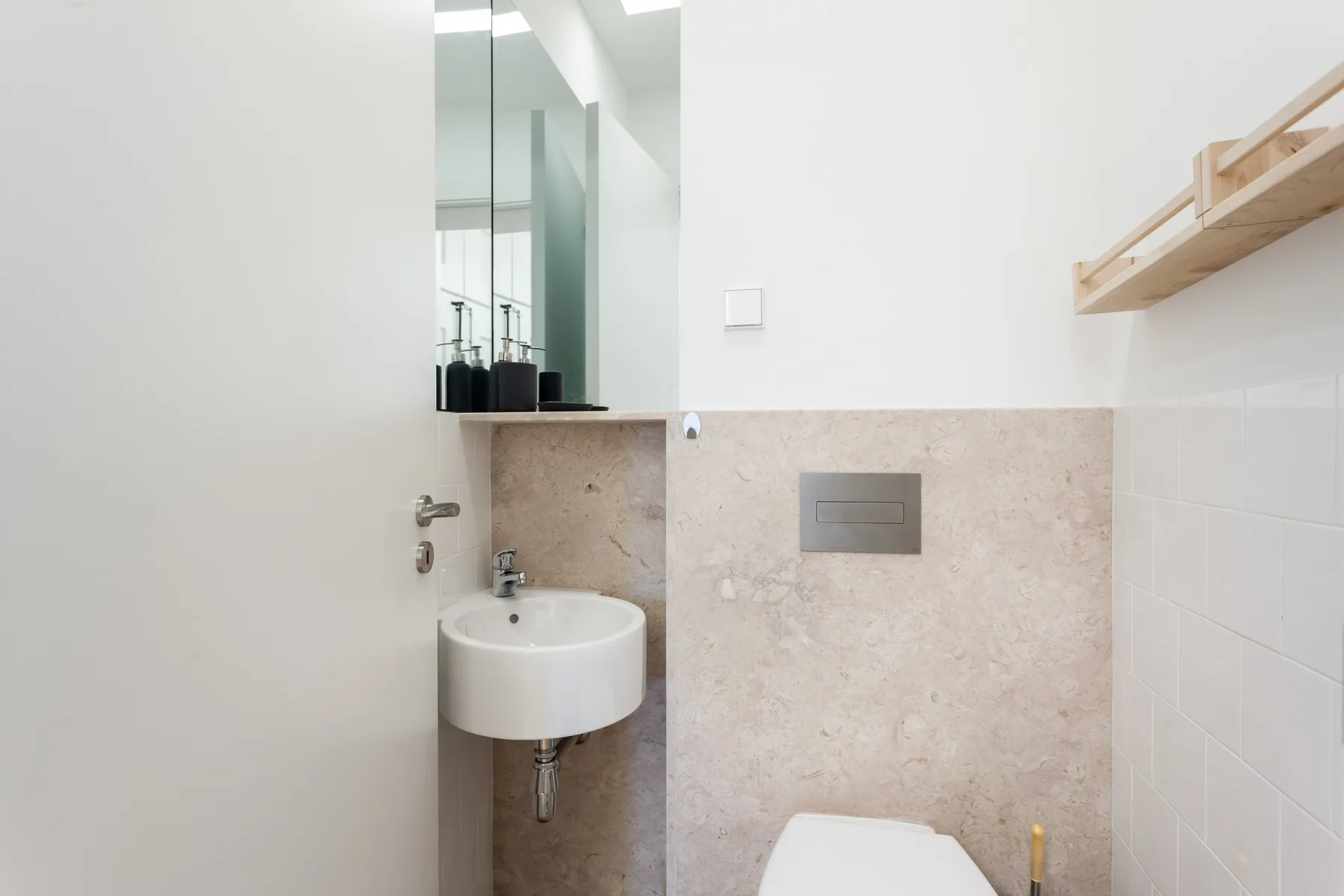 Un baño luminoso con un lavabo suspendido y paredes revestidas de azulejos.