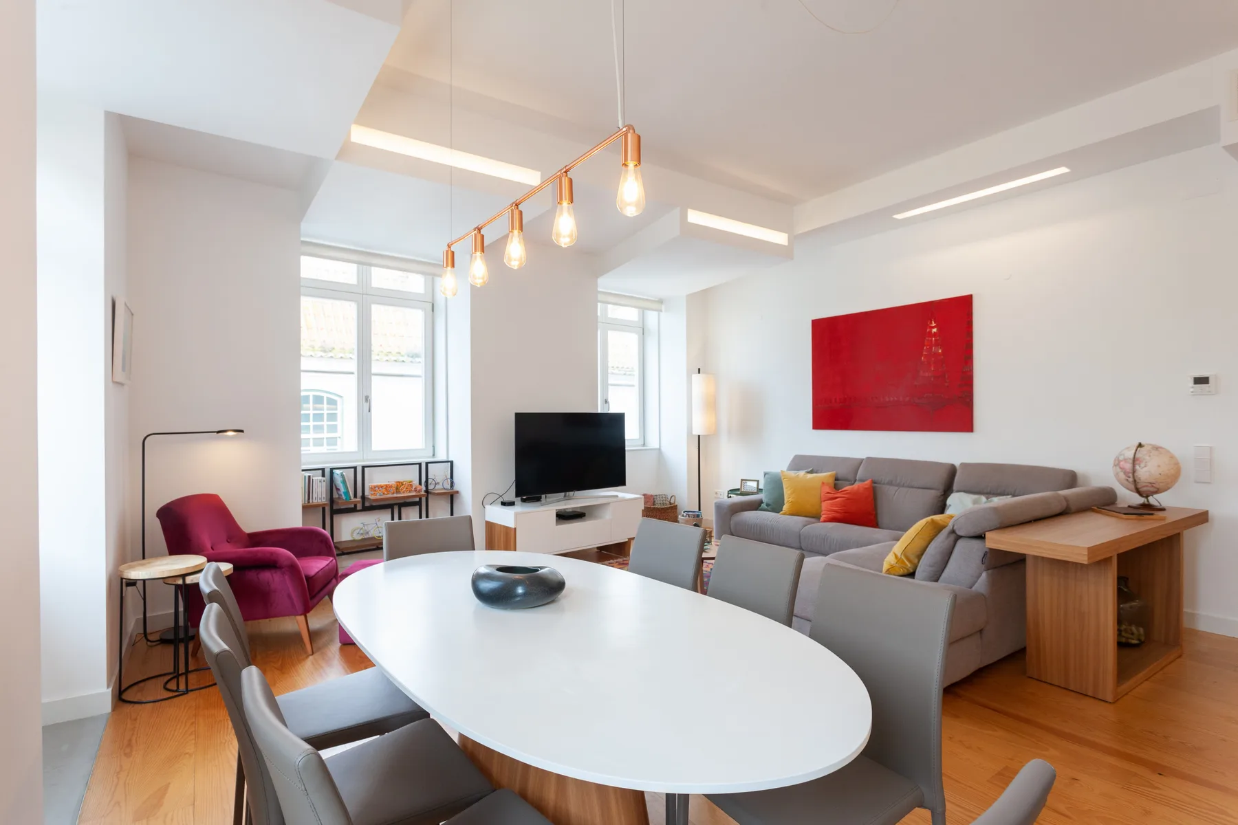 A bright living room with a dining table, seating, and a television.