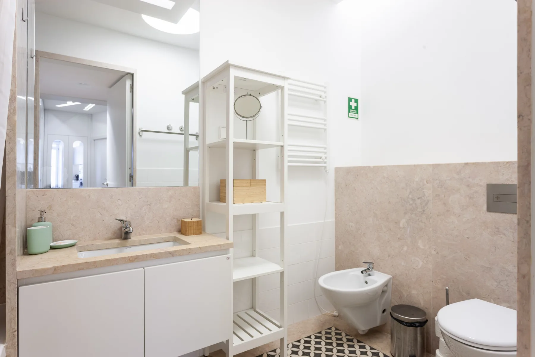 Un baño luminoso con lavabo, estantería abierta y sanitarios.