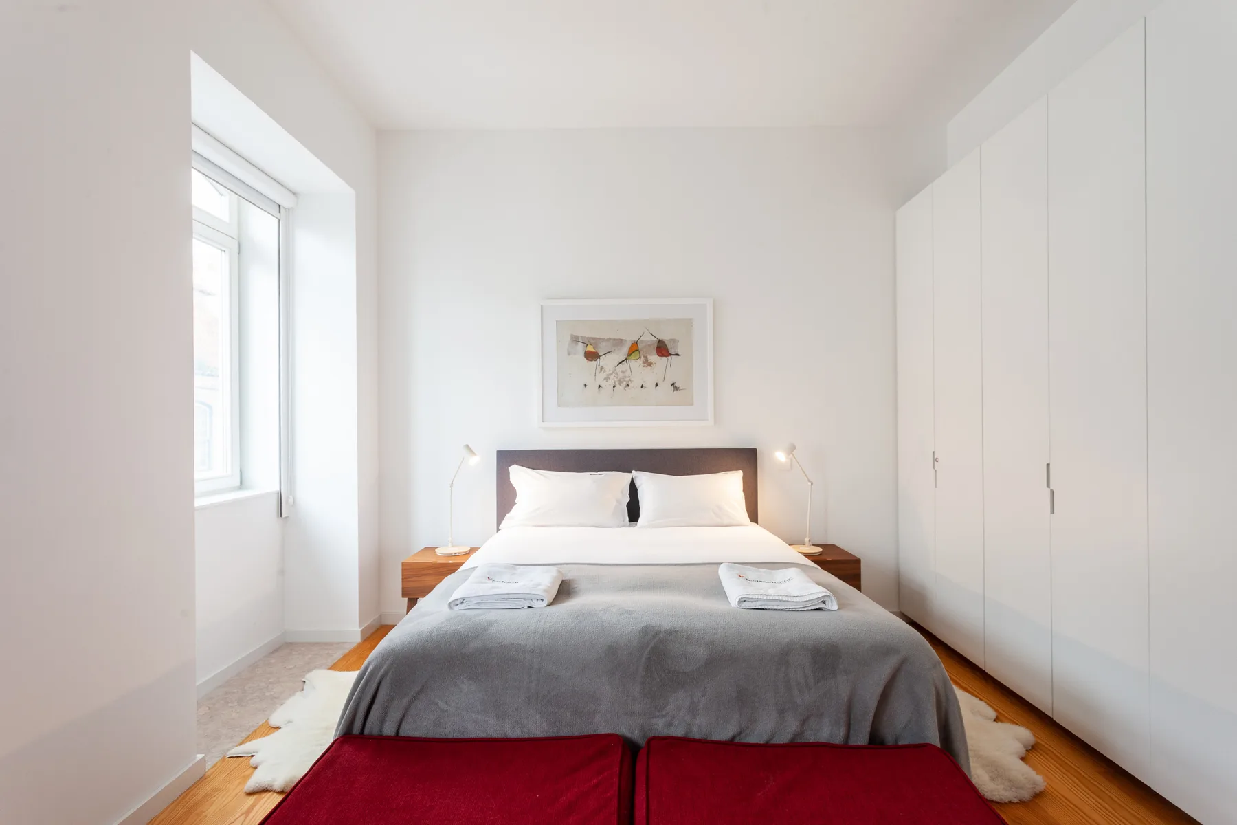 Un dormitorio luminoso con una cama bien arreglada y una ventana grande.
