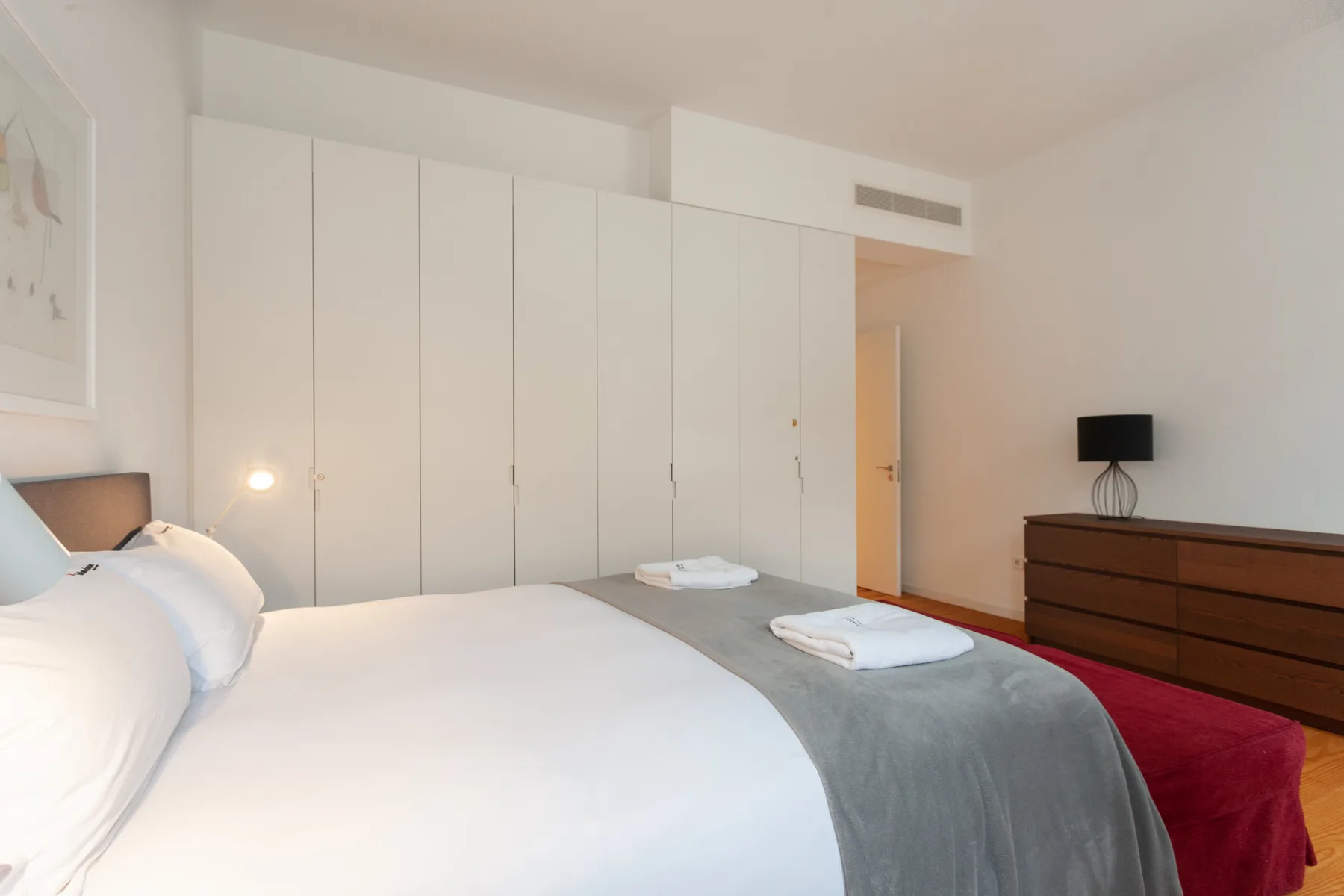 Un dormitorio con una cama, toallas dobladas y una cómoda.