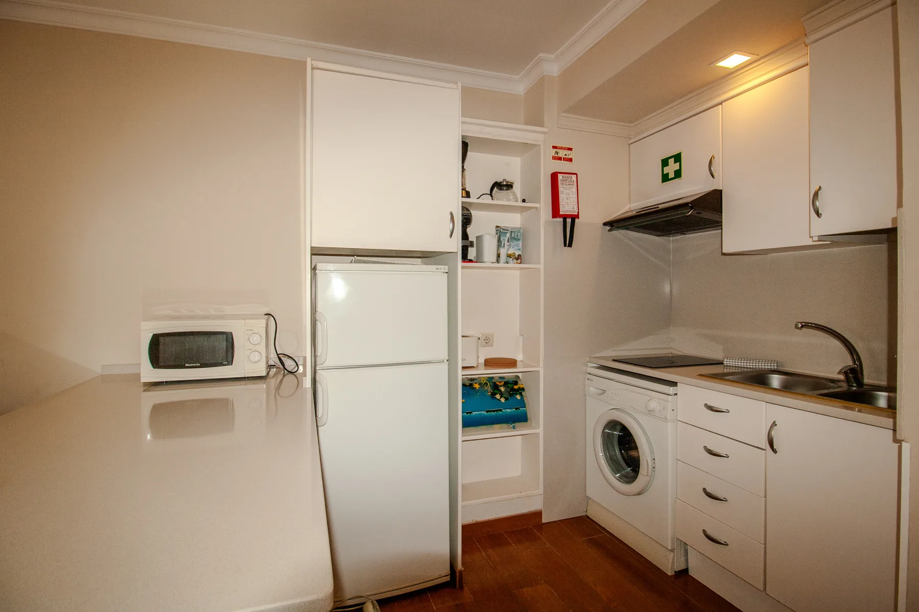A compact kitchen with white cabinets, a refrigerator, and a washing machine.