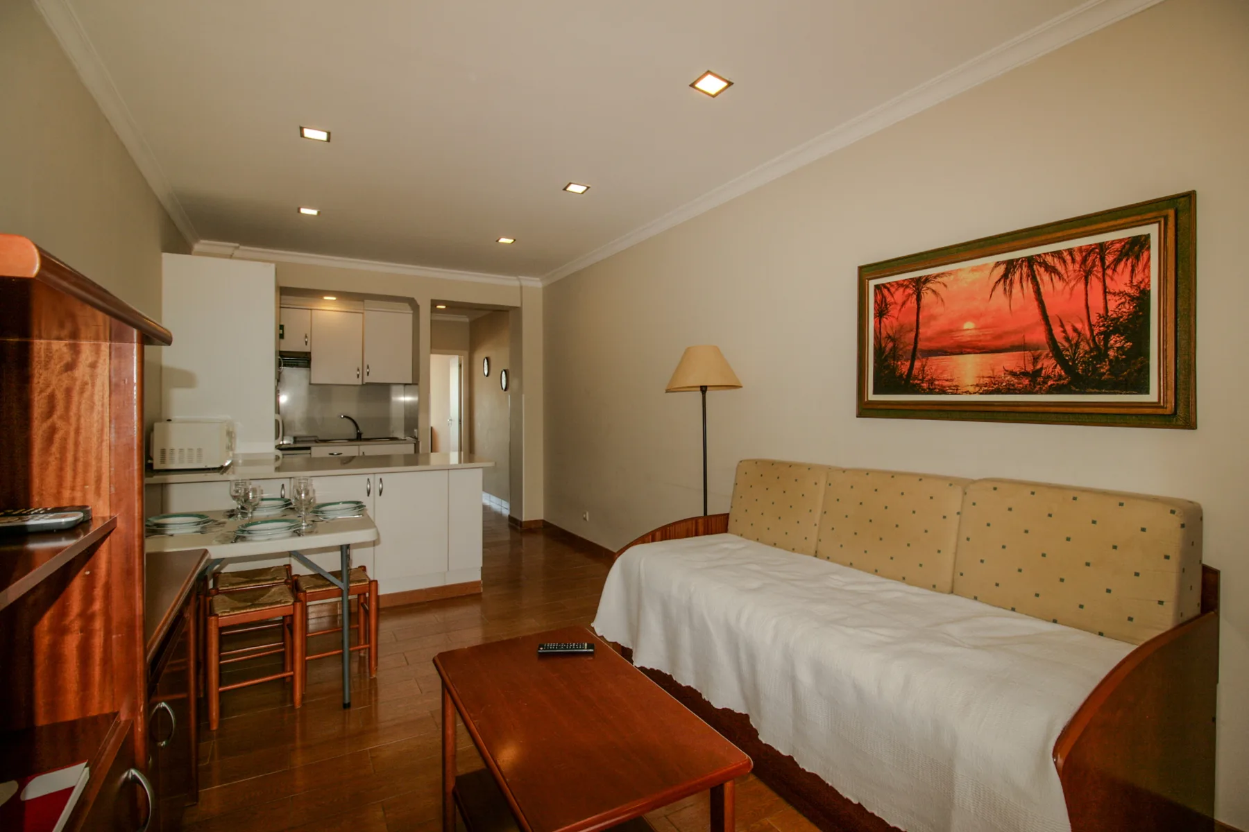 Living room with a covered seating area, coffee table, and open kitchen.