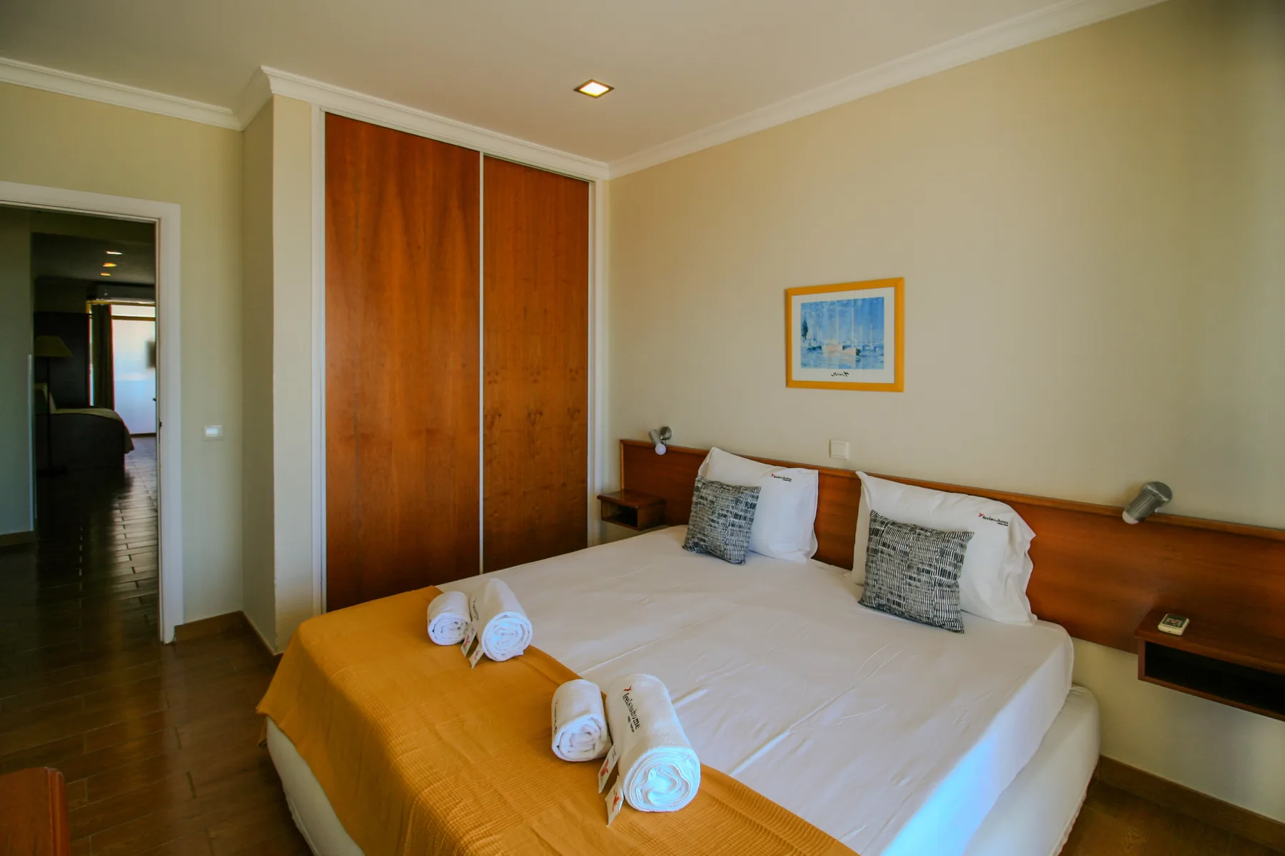 A bedroom with a bed, wooden wardrobe, and an open doorway.