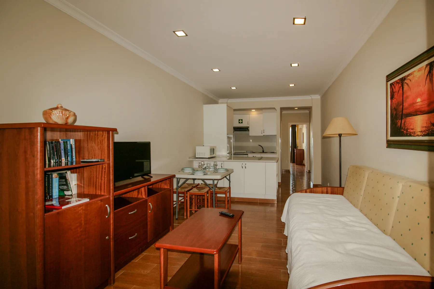 Living room with seating, a television, and a compact kitchen area.