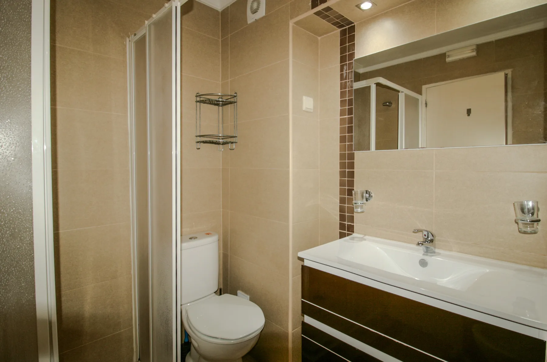 A tiled bathroom with a shower, toilet, and sink.