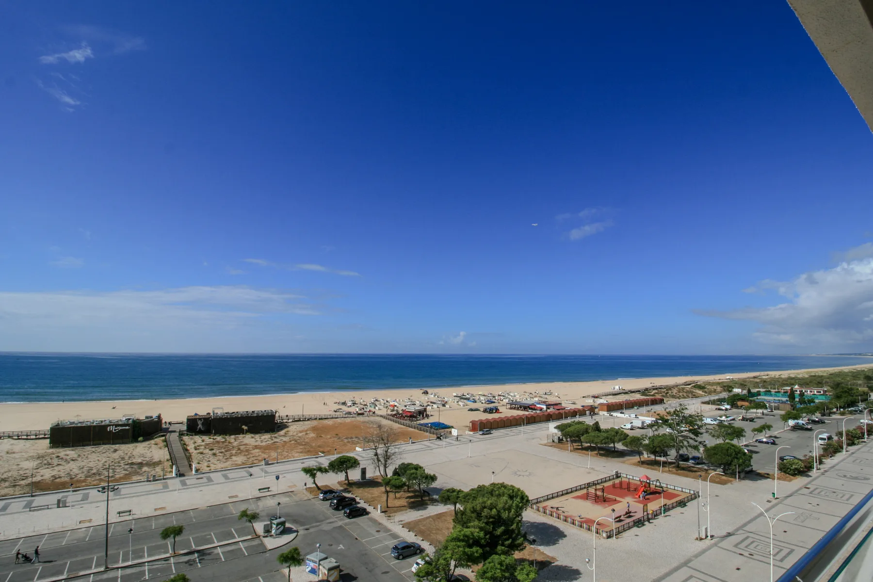 A coastal view overlooks the beach, ocean, and nearby streets.