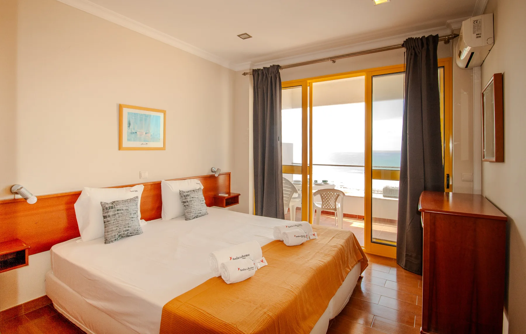 A bedroom with a bed beside sliding glass doors opening onto a balcony.
