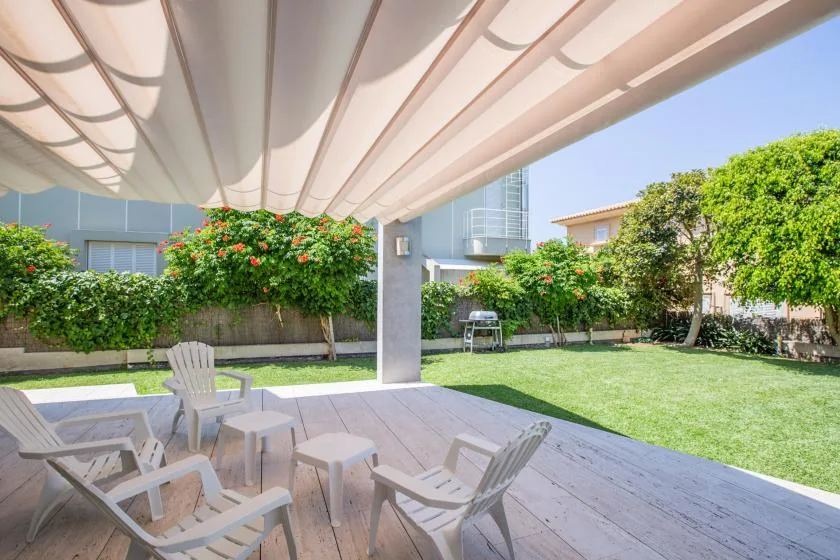 Un patio sombreado con asientos al aire libre da a un jardín verde.