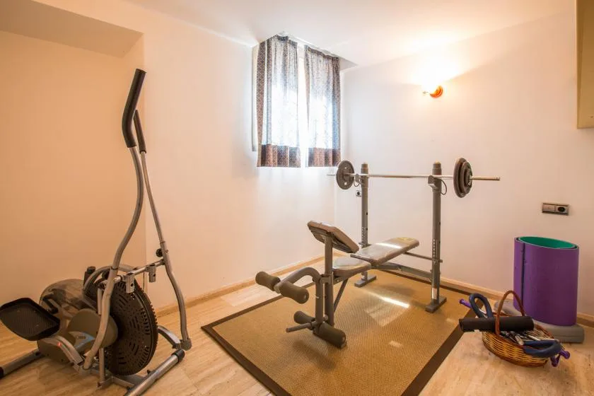 Un gimnasio en casa con equipos de ejercicio alrededor de un banco de pesas.