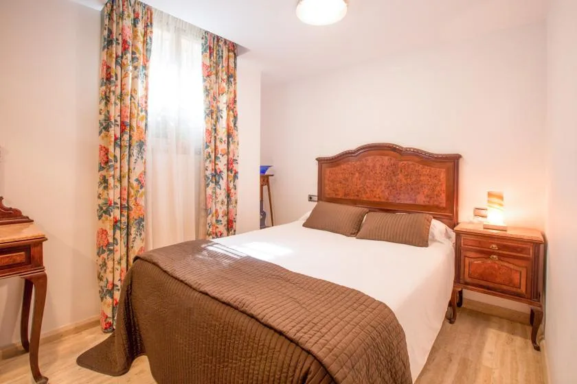 Un dormitorio con una cama grande, cabecero de madera y cortinas florales.