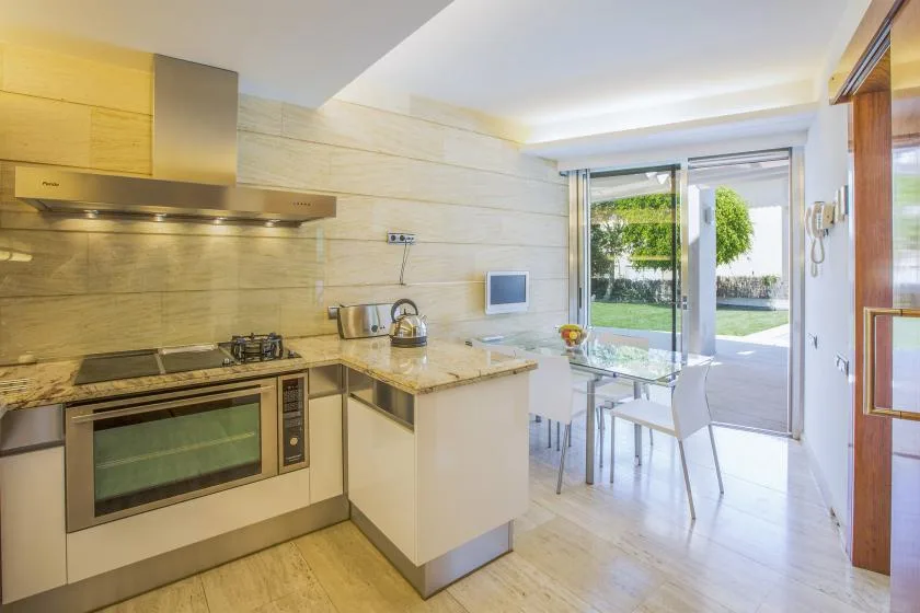 Una cocina luminosa se abre a un comedor junto a grandes puertas de vidrio.