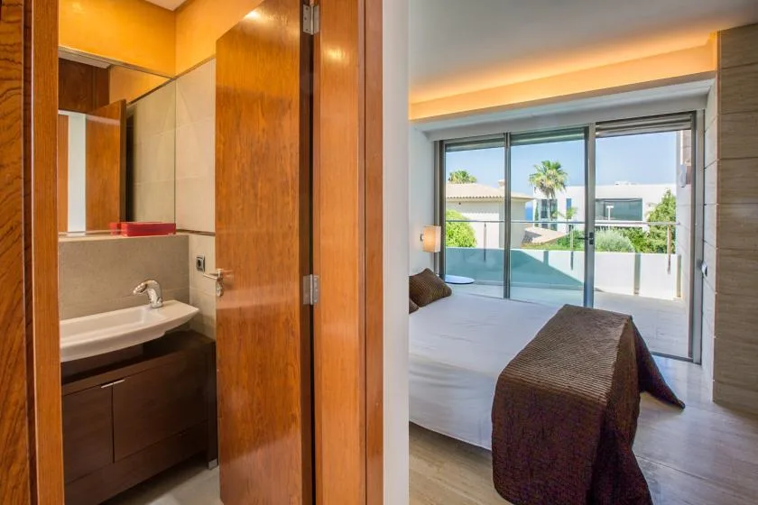 Un dormitorio con una cama junto a una gran puerta de vidrio que da a un balcón.