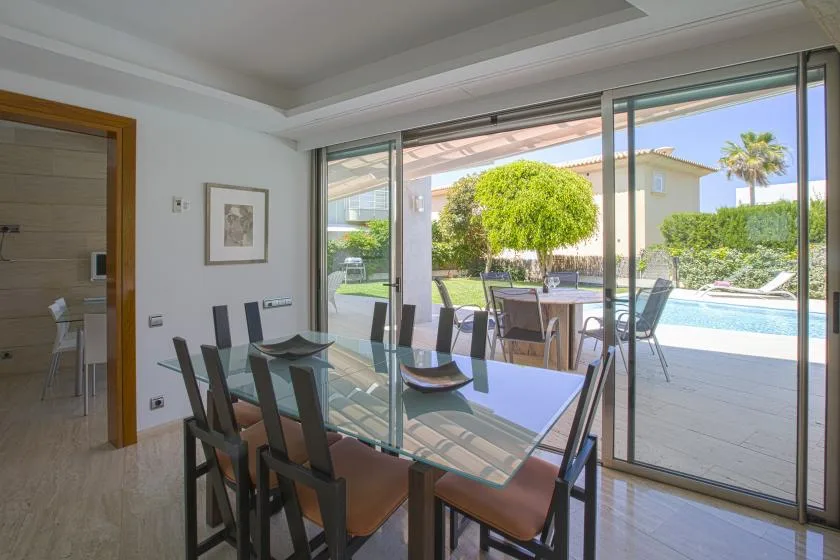 Un comedor con una mesa de vidrio se abre a un patio y una piscina.
