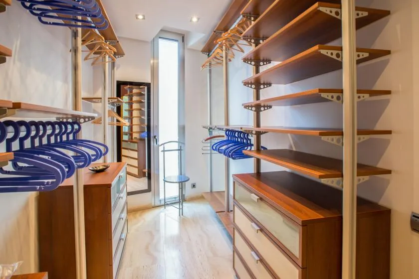 Un vestidor con estantes de madera y barras para colgar ropa.