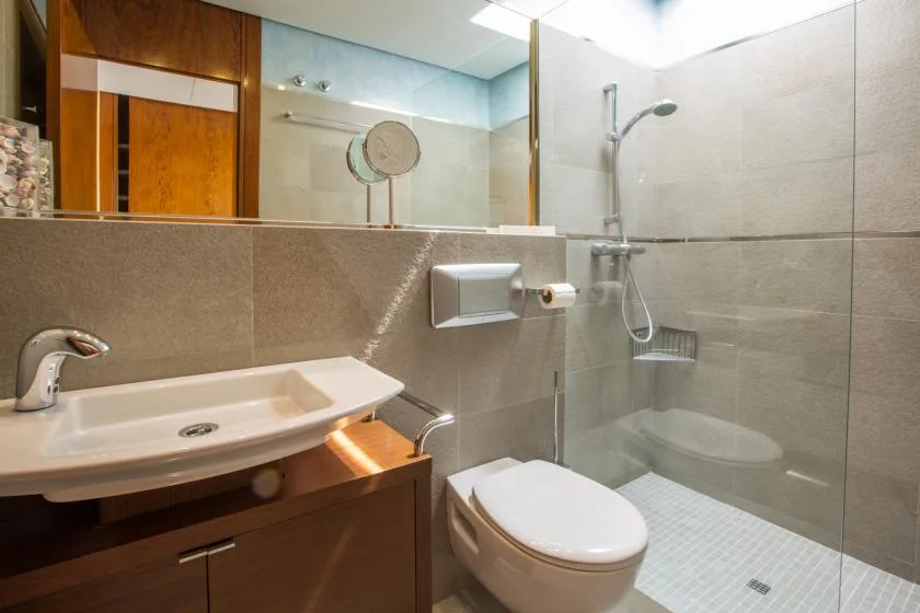Un baño alicatado con lavabo, inodoro y mampara de ducha de vidrio.