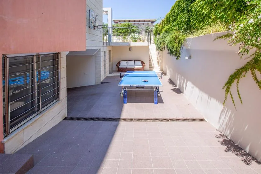 Un patio al aire libre con una mesa de ping-pong y asientos al fondo.