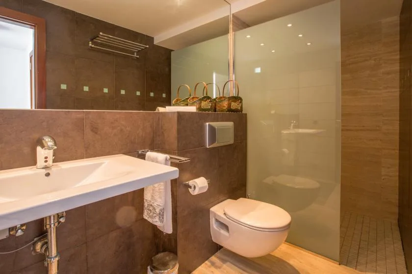 Un baño con lavabo, inodoro suspendido y zona de ducha de vidrio.