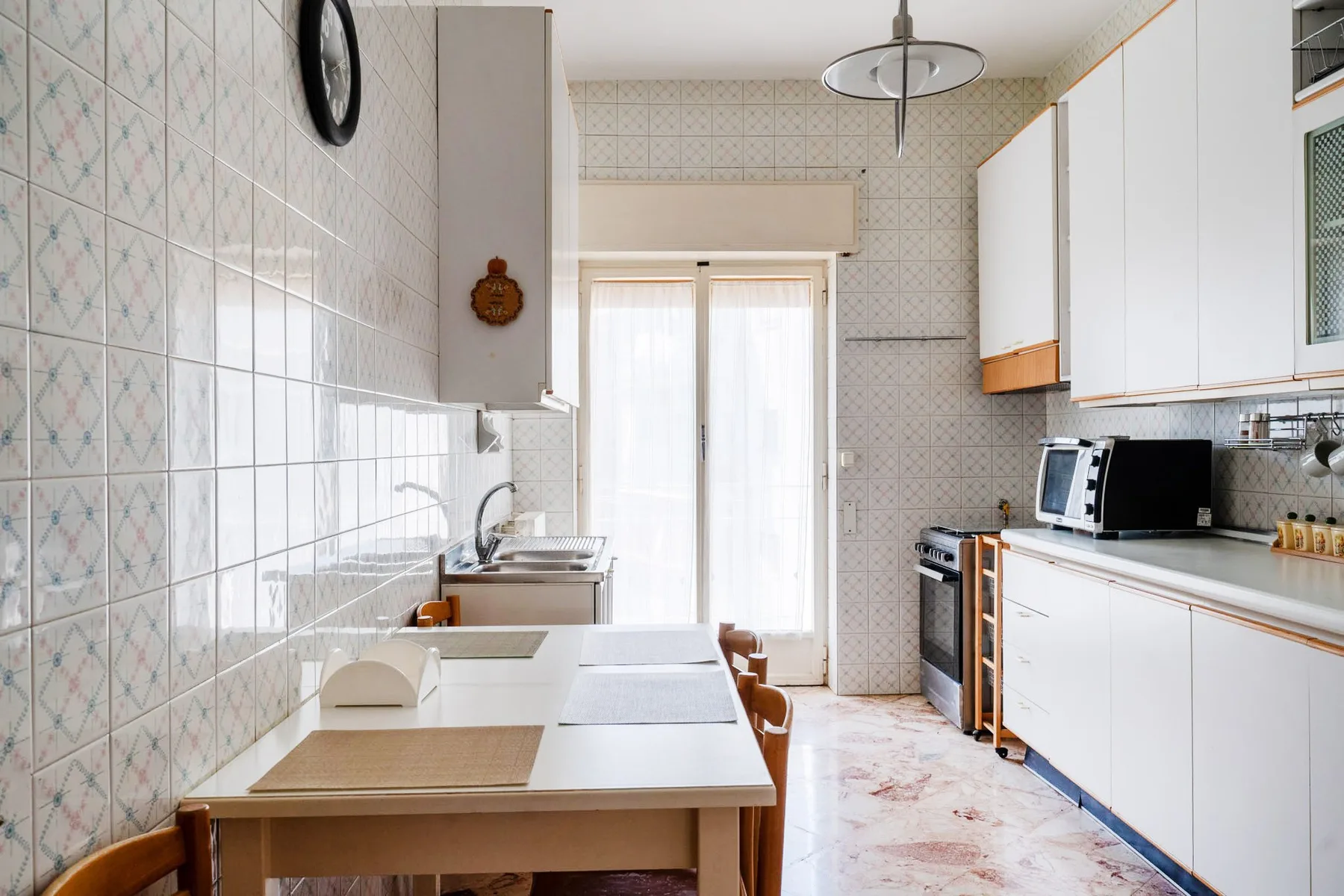 A bright kitchen with a long counter, dining table, and a window at the far end.