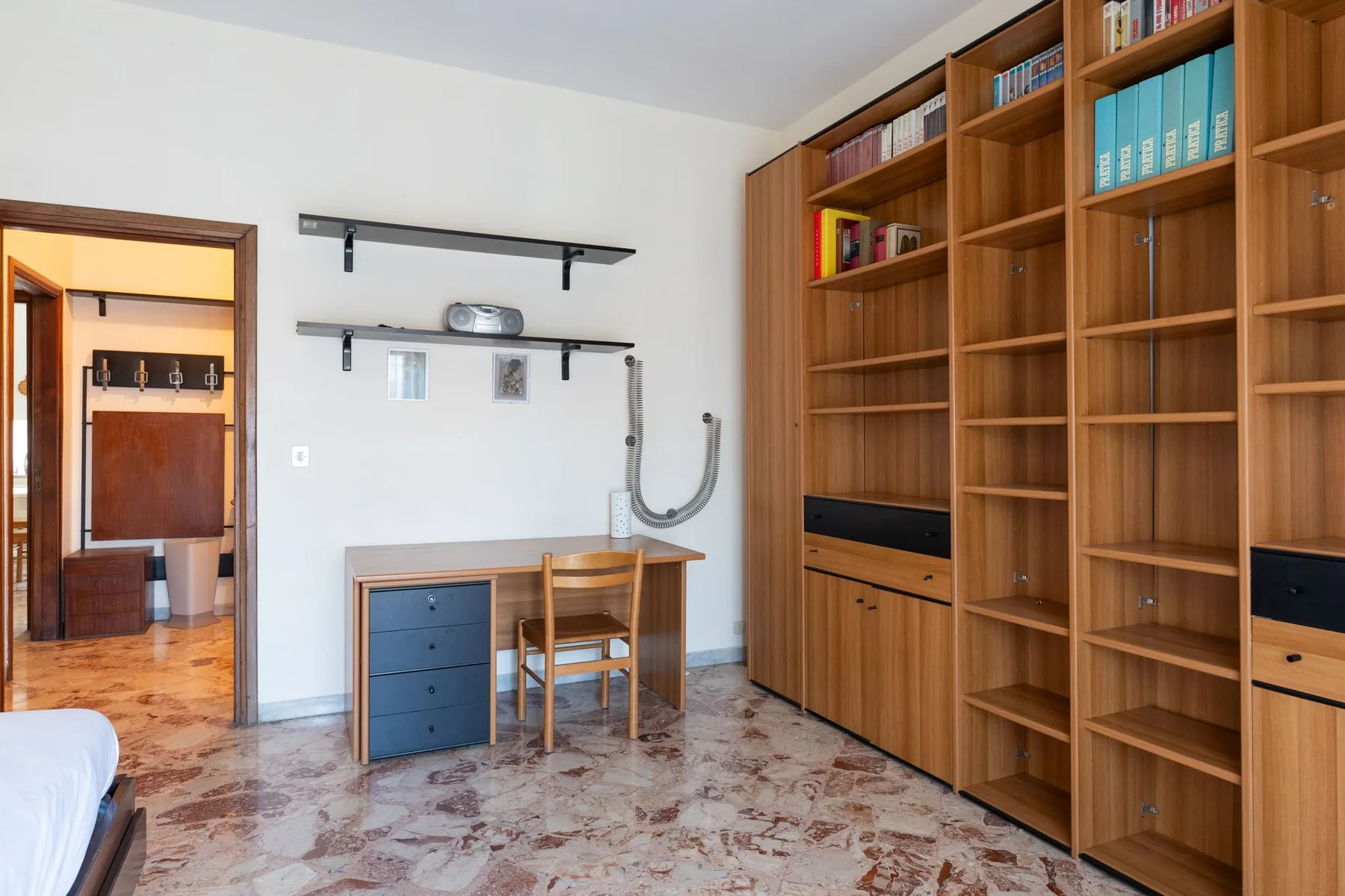 A room with floor-to-ceiling wooden shelving and a small desk.