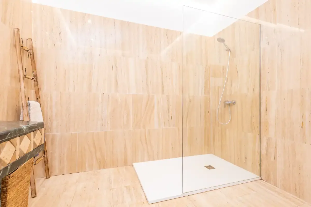 Un baño alicatado con ducha y una pequeña zona de lavabo.