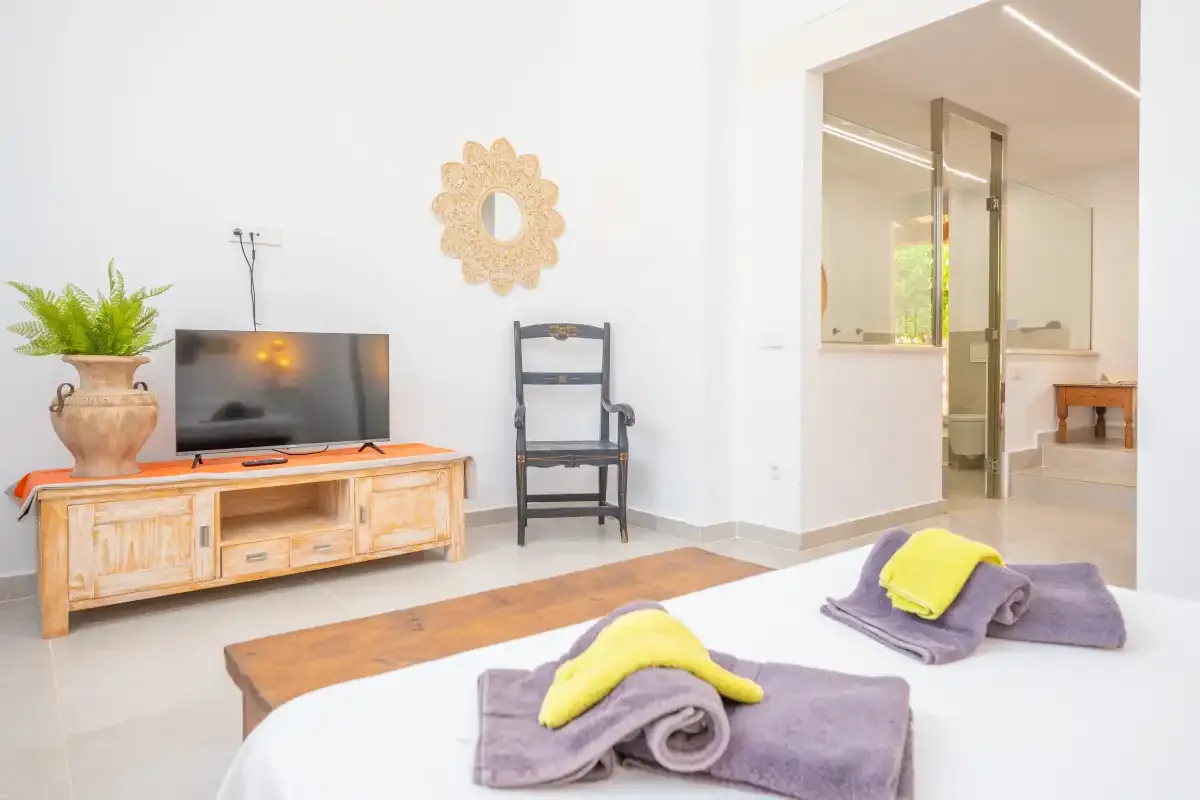 Una luminosa sala de estar con televisor y asientos junto a un baño abierto.