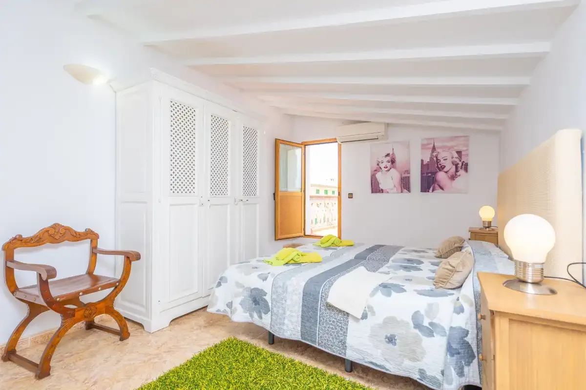 Un dormitorio luminoso con dos camas, una ventana y una silla de madera.