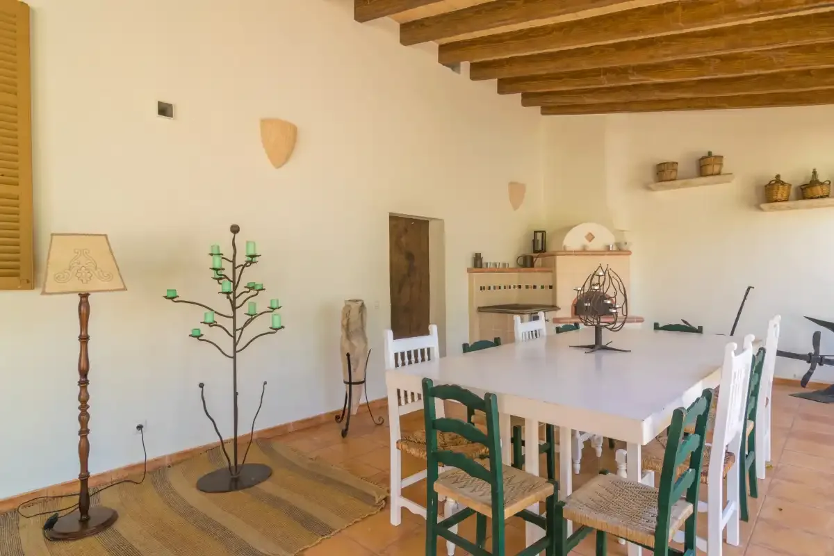 Un comedor con una mesa larga y sillas de madera bajo vigas expuestas.