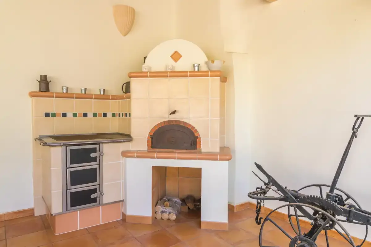 Una zona de cocina alicatada con horno empotrado y chimenea.