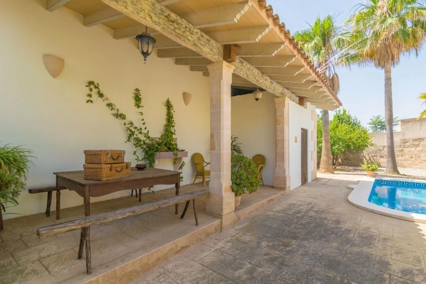 Un patio cubierto con una mesa y sillas da a una piscina.