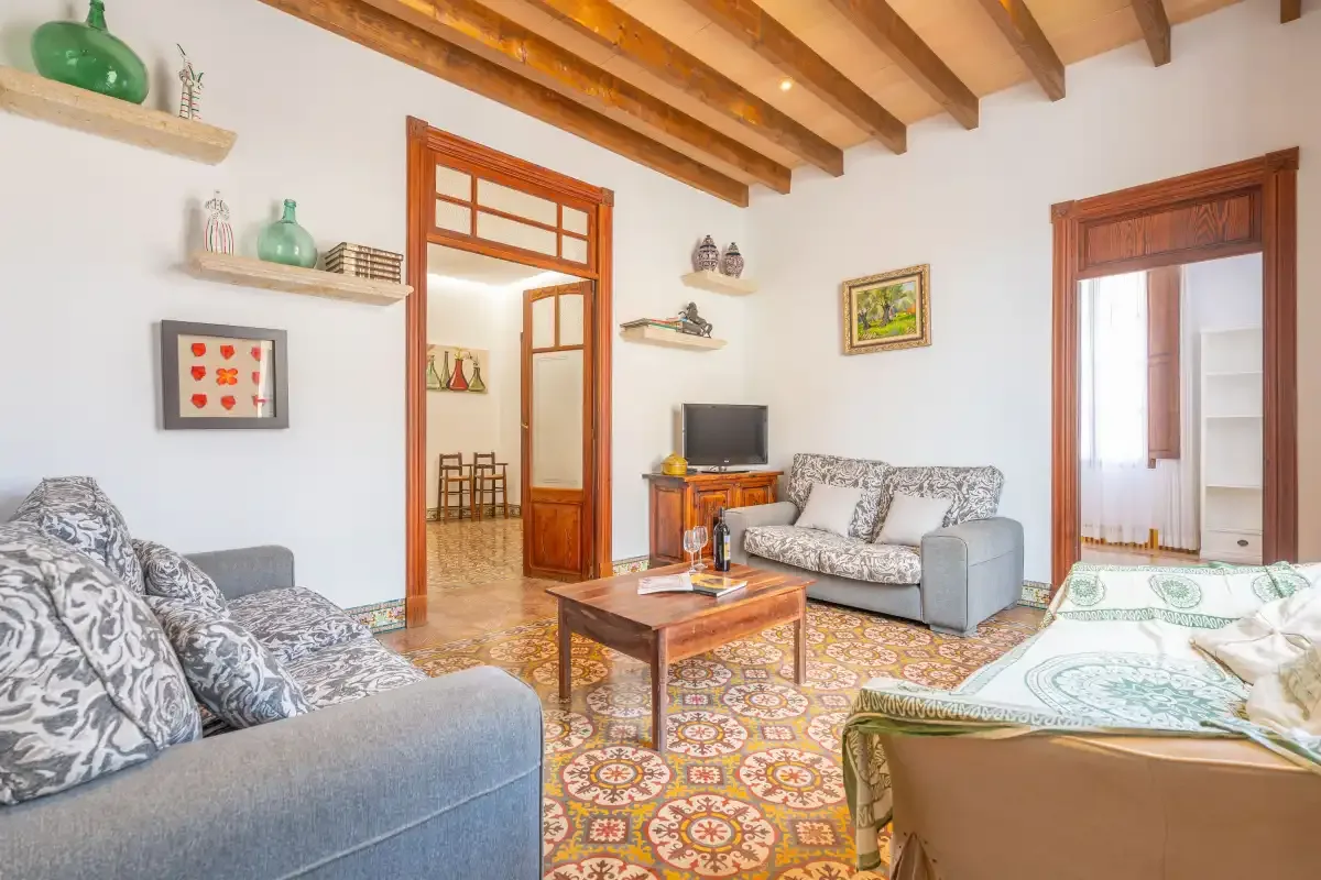 Una sala de estar con asientos, una mesa de centro y suelo de baldosas estampadas.