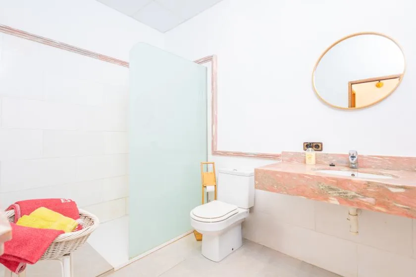 Un baño alicatado con inodoro, lavabo y espejo ovalado en la pared.