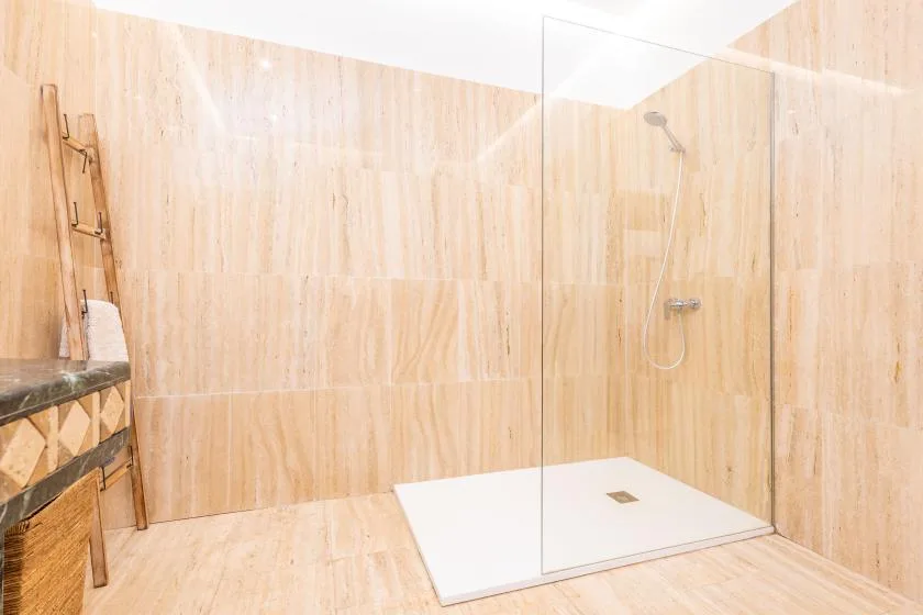 Un baño alicatado con ducha y mampara de cristal.