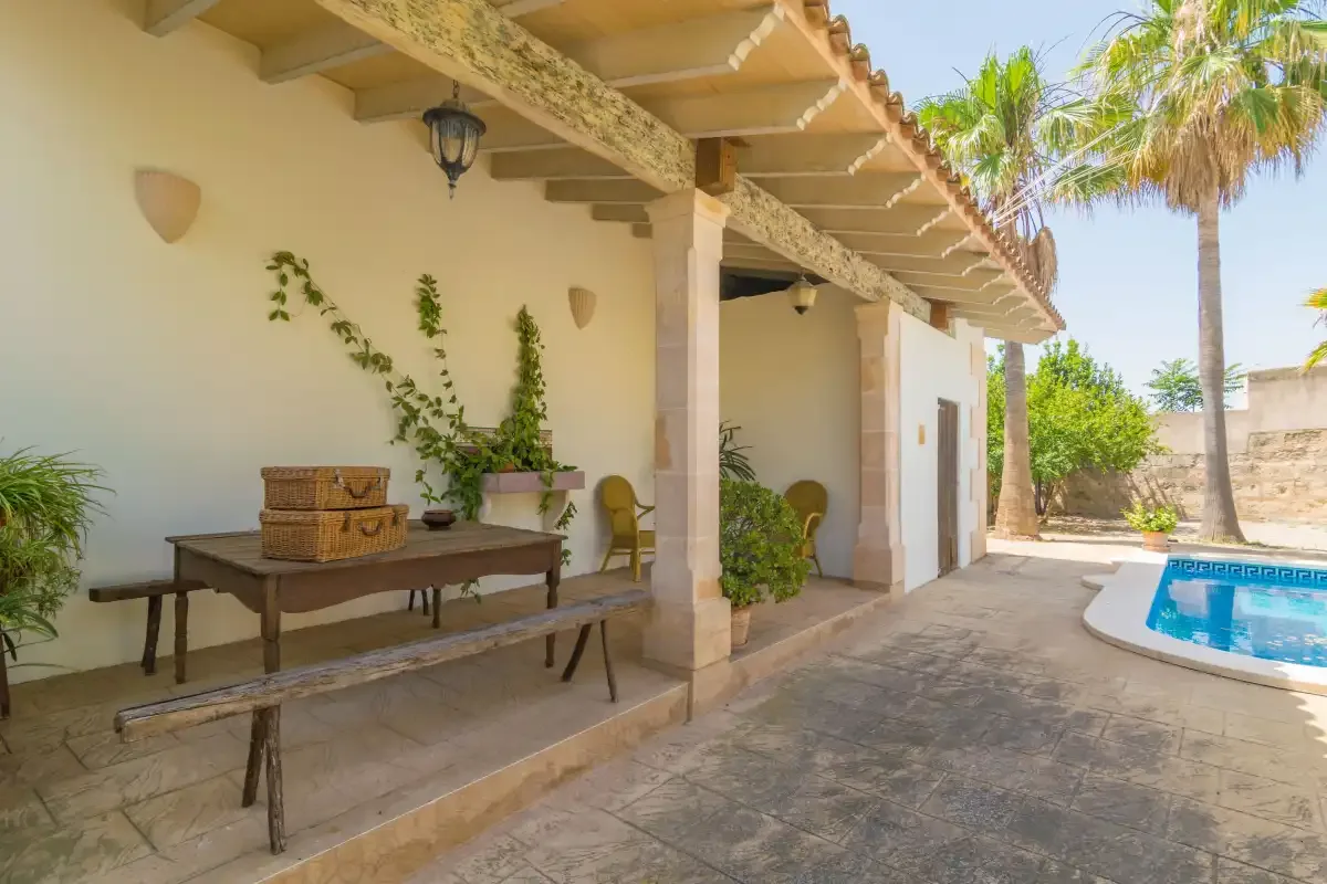 Un patio cubierto con una mesa y asientos junto a una piscina.