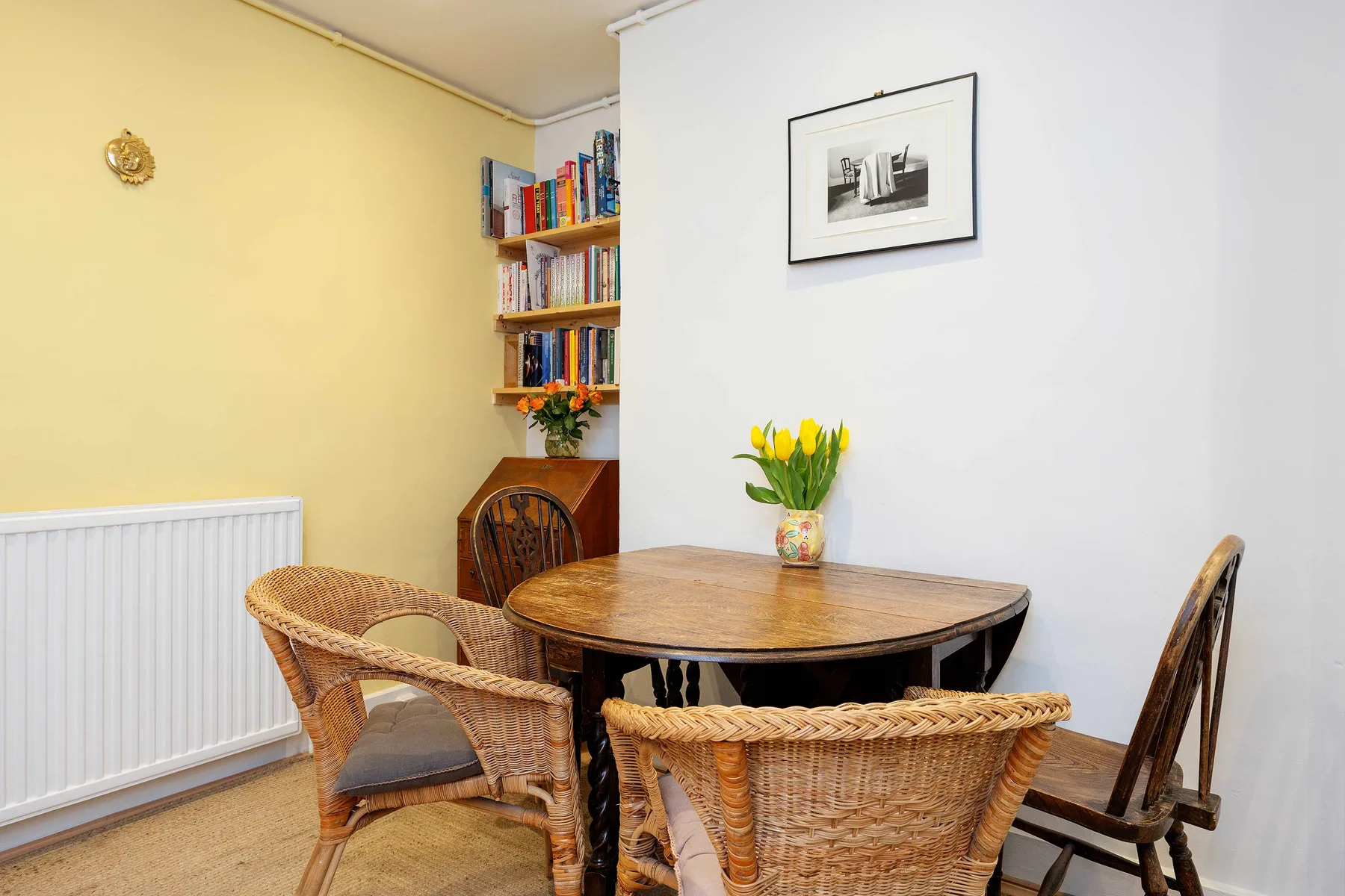 A dining area with a wooden table, woven seating, and flowers.