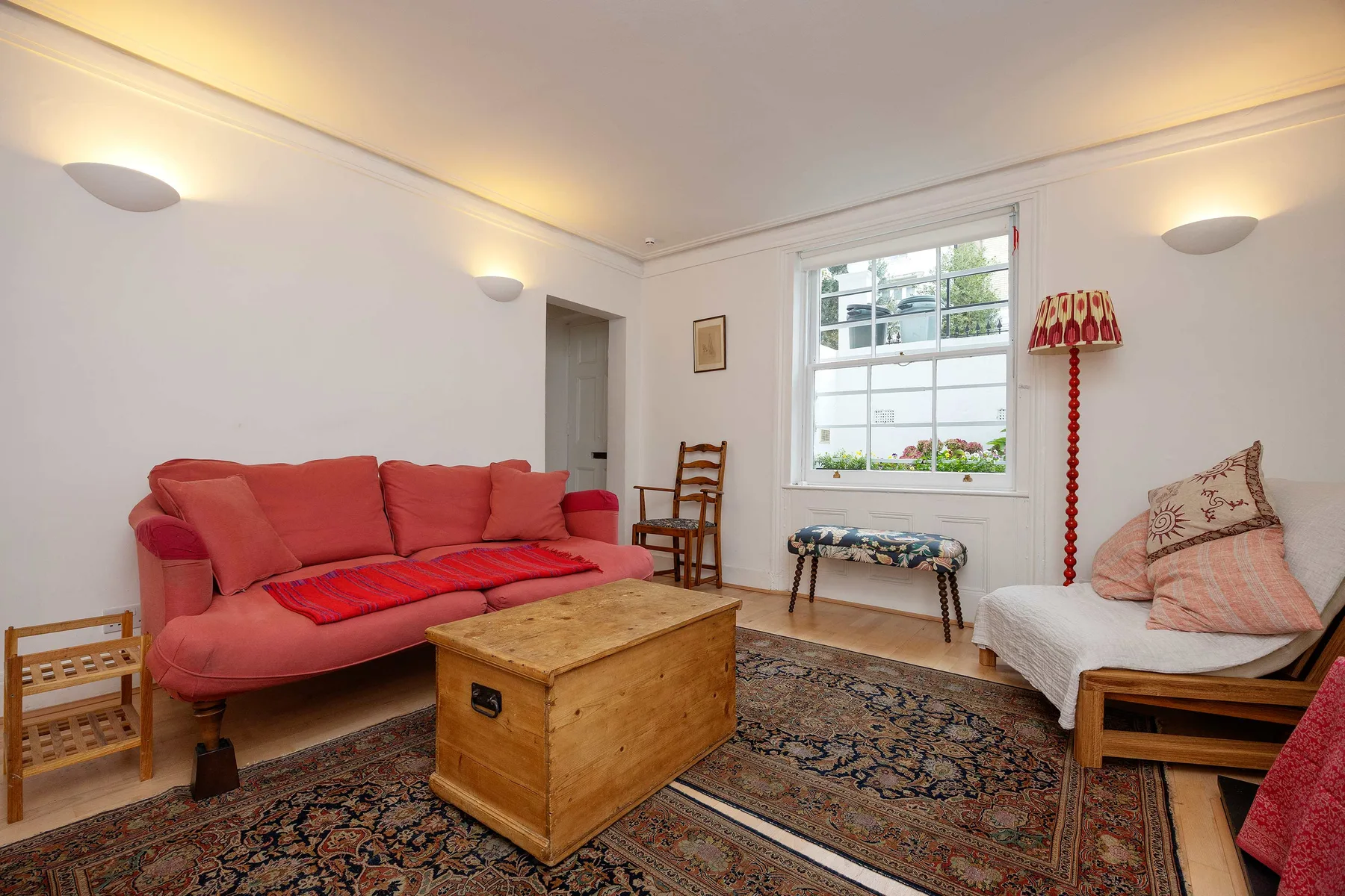 A living room with red seating, a wooden coffee table, and a patterned rug.