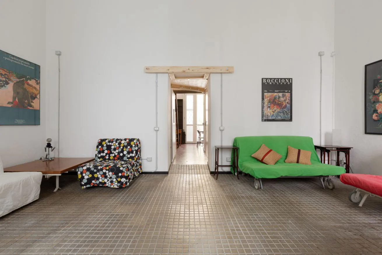 Una sala de estar con asientos coloridos y una puerta que da a un pasillo.