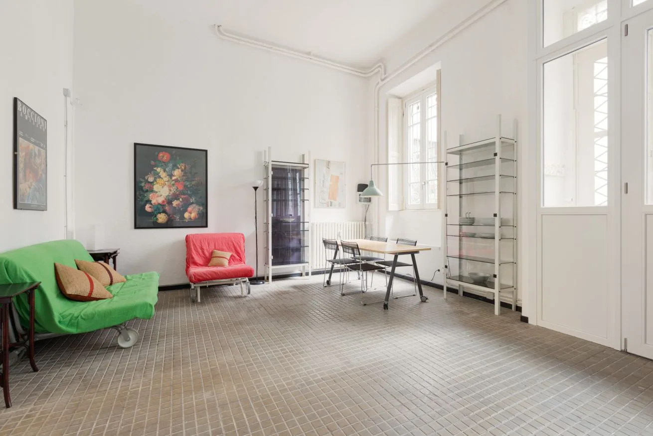 Una sala luminosa con asientos, una mesa de trabajo y ventanas altas.