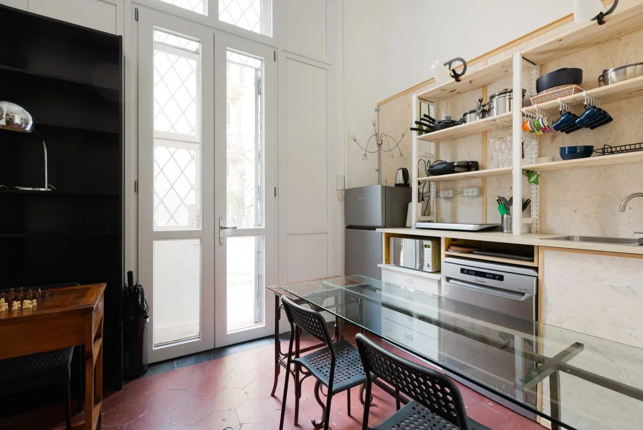 Una cocina luminosa con estantes abiertos y una mesa de vidrio.