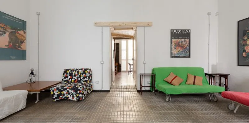Una sala de estar con asientos coloridos y una puerta abierta a un pasillo.