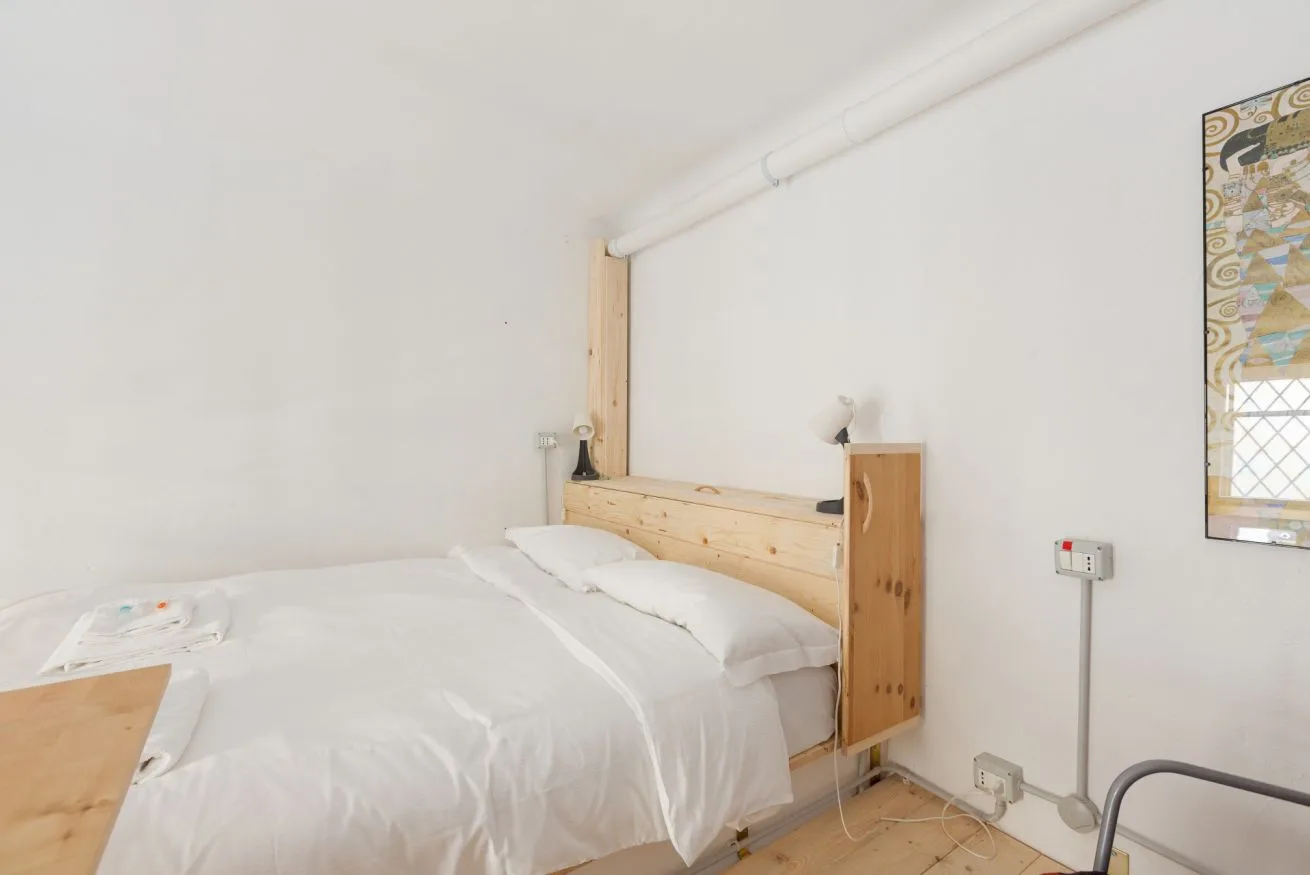 Un dormitorio con una cama junto a un cabecero de madera clara y un mapa en la pared.