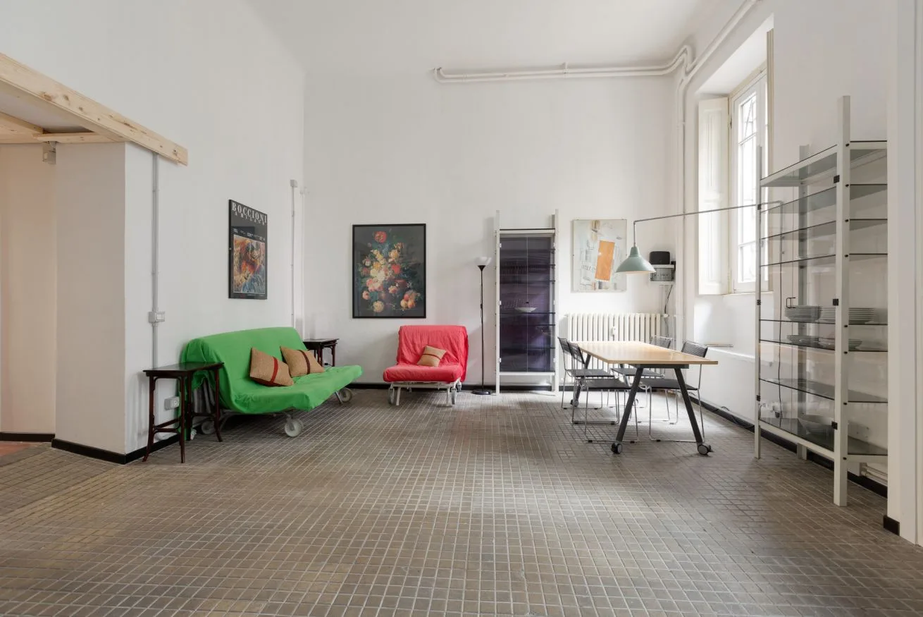 Una sala de estudio luminosa tiene asientos coloridos, una mesa y estanterías altas.