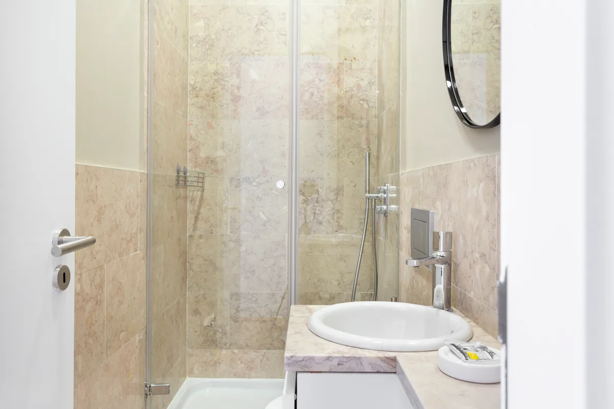 A bathroom with a glass shower and a sink.