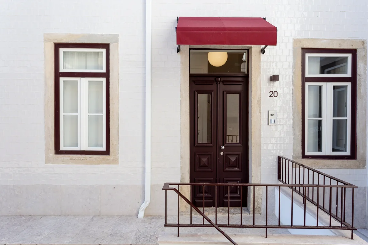 A building entrance with a dark double door beneath a red awning.