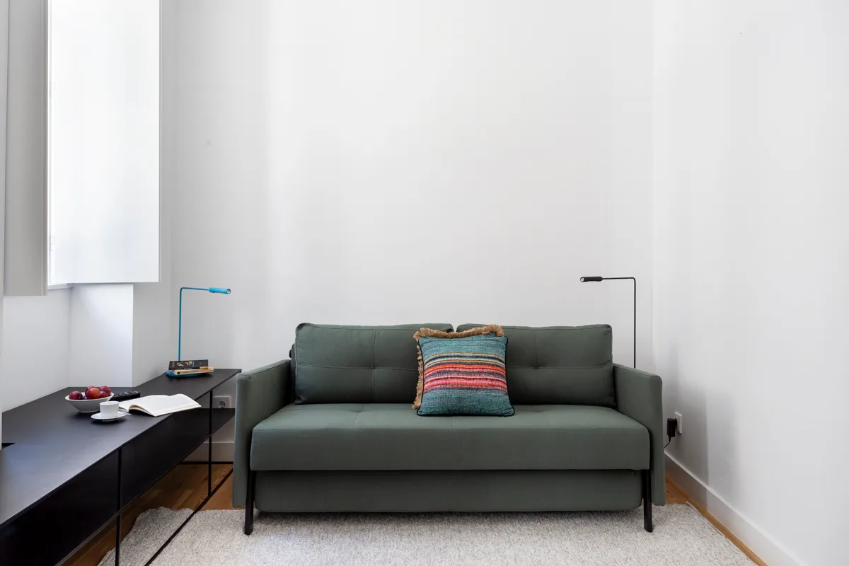 A living room with a dark sofa and a colorful striped cushion.
